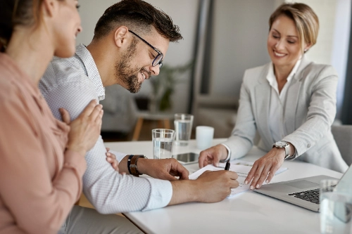 Pareja firmando un acuerdo financiero con un asesor, representando la confianza detrás de un contrato de protección crediticia