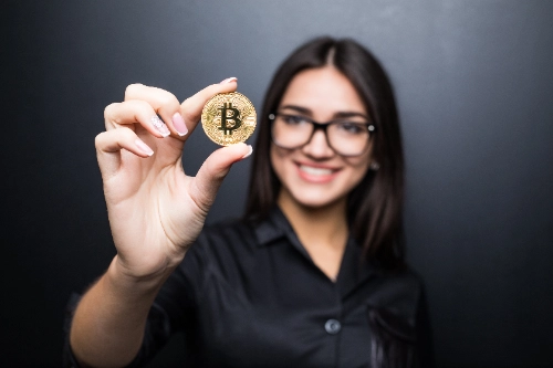 Mujer sosteniendo una moneda de Bitcoin, representando la expectativa del mercado ante el halving