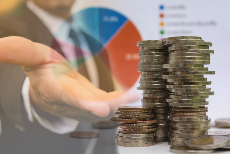 Empresario señalando monedas junto a gráficos de oficina