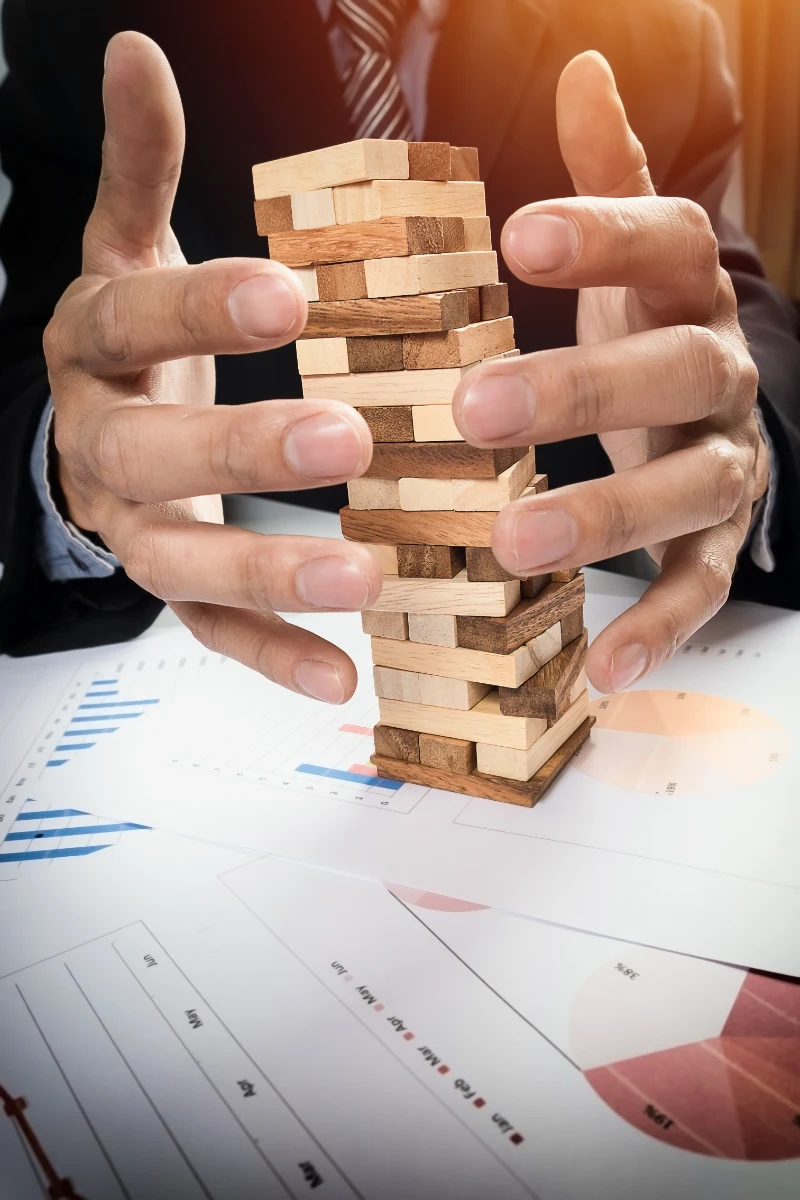 Empresario colocando un bloque de madera en una torre, representando el riesgo y la planificación estratégica